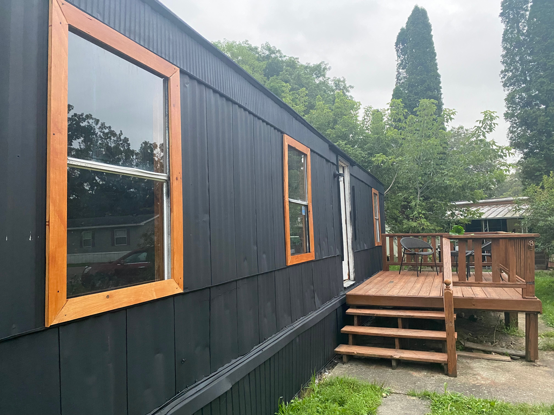 Renovated black mobile home with wood-trimmed windows and deck