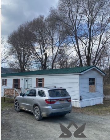 Mobile home with green metal roof and SUV parked in front