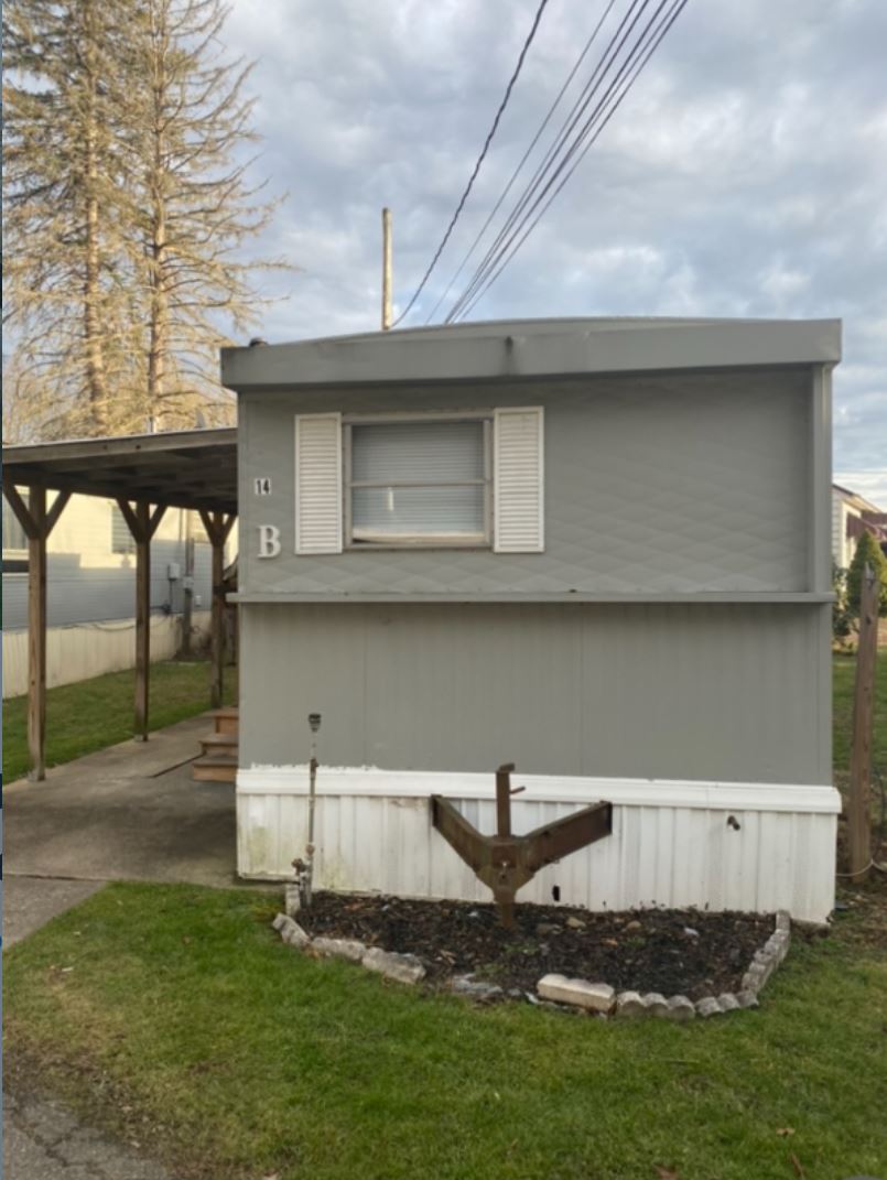 Gray single-wide mobile home exterior in as-is condition